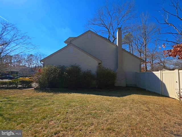 view of side of property featuring fence and a yard