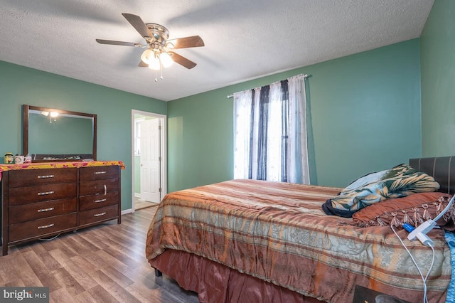 bedroom with a textured ceiling, a ceiling fan, and wood finished floors