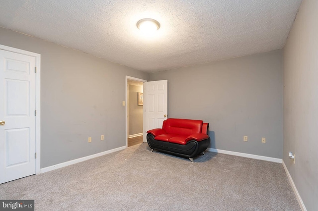 living area featuring carpet, baseboards, and a textured ceiling