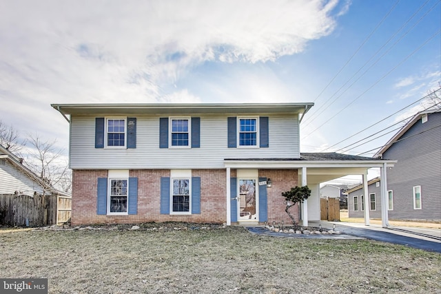 view of front facade featuring an attached carport, brick siding, driveway, and fence