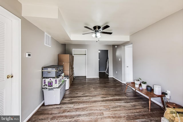 interior space with baseboards, visible vents, a ceiling fan, and wood finished floors