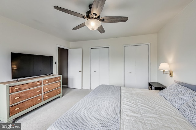 bedroom with multiple closets, light colored carpet, and ceiling fan