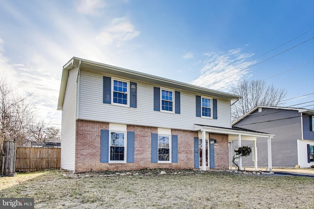 view of front facade with a front yard, fence, and brick siding