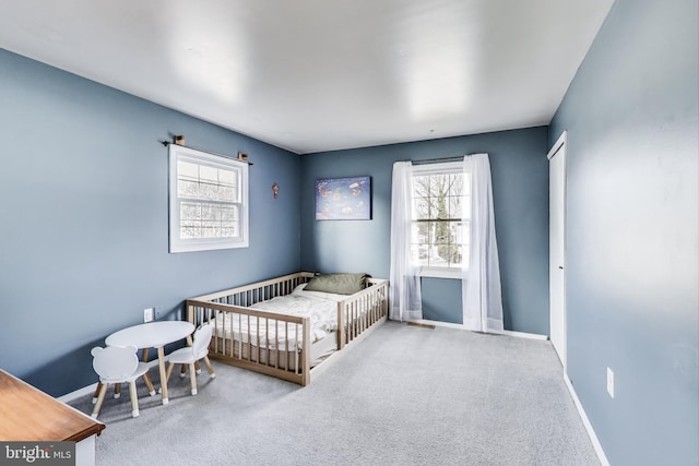 bedroom featuring a crib, carpet, and baseboards