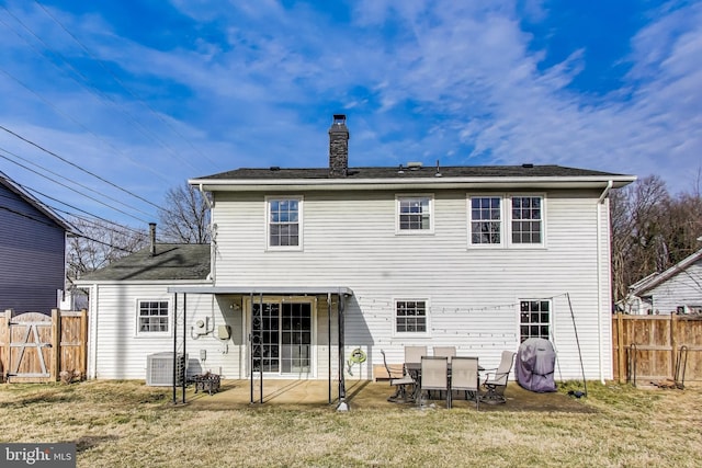 back of property featuring a patio area, a chimney, fence, and a lawn