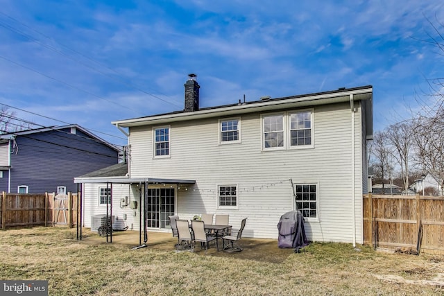 rear view of property with a fenced backyard, a chimney, a patio, and a yard