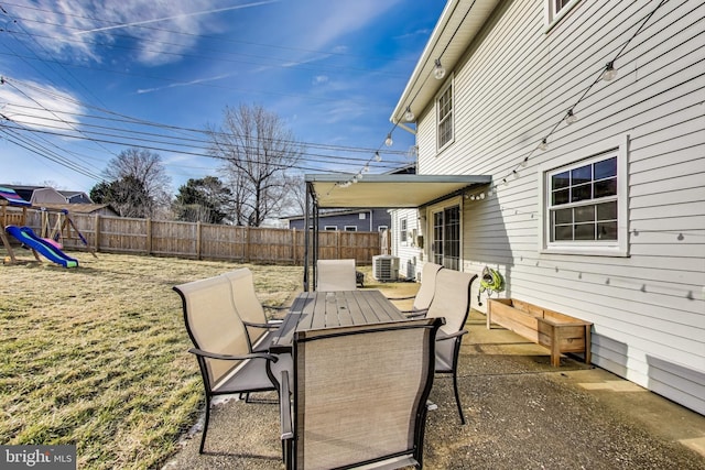 view of patio / terrace with cooling unit, outdoor dining area, a playground, and a fenced backyard