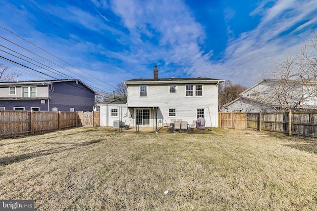 rear view of property featuring a patio, a chimney, a fenced backyard, and a lawn