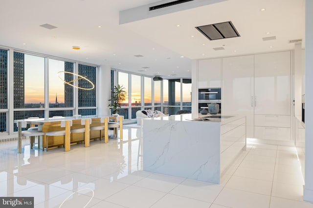 kitchen featuring a wall of windows, light tile patterned flooring, white cabinets, and modern cabinets