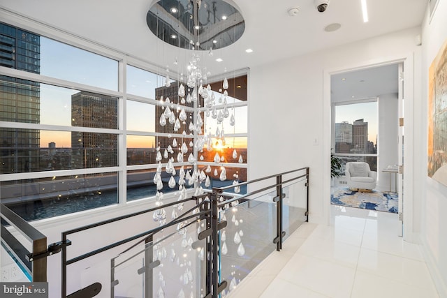 hallway featuring an upstairs landing, a city view, and tile patterned floors