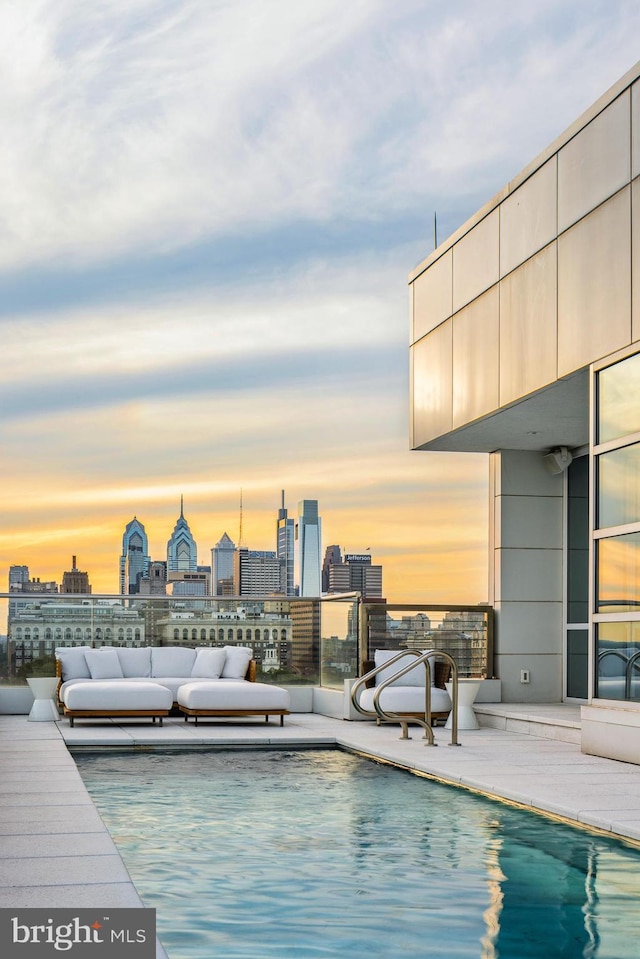 pool at dusk with a view of city and an outdoor living space