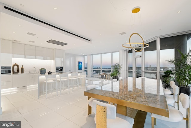 dining space with light tile patterned floors, a wall of windows, and a chandelier