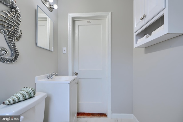 bathroom featuring marble finish floor, baseboards, vanity, and toilet