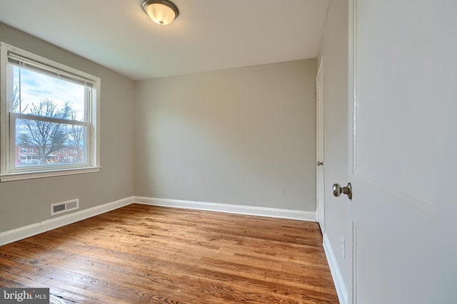 unfurnished room featuring visible vents, baseboards, and wood finished floors