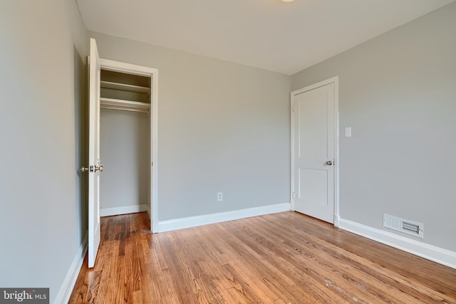 unfurnished bedroom featuring light wood finished floors, baseboards, visible vents, and a closet