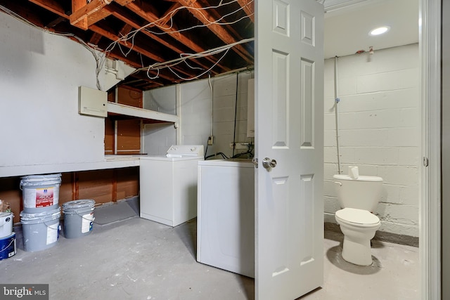 clothes washing area with concrete block wall, washer / dryer, and laundry area