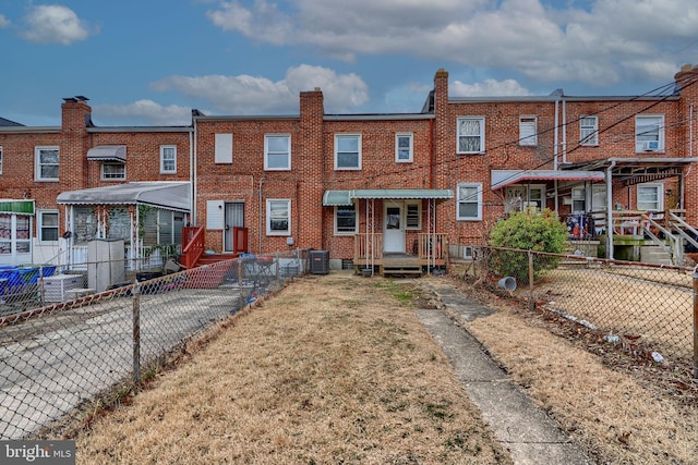 rear view of house featuring cooling unit, brick siding, and fence