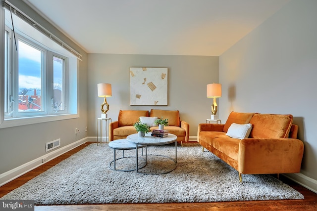 living area with visible vents, baseboards, and wood finished floors