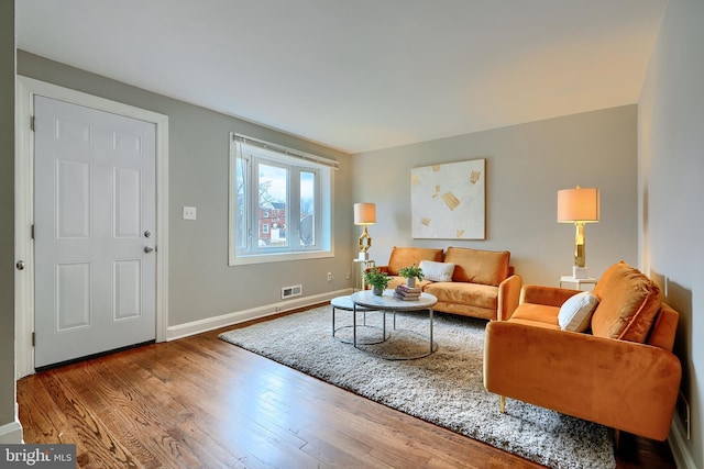 living area featuring visible vents, baseboards, and wood finished floors