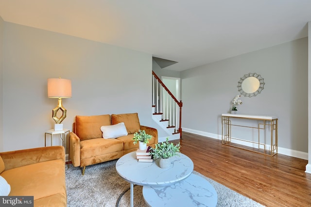 living room with stairs, wood finished floors, and baseboards