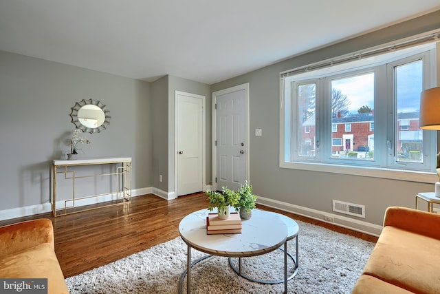 living area featuring baseboards, visible vents, and wood finished floors