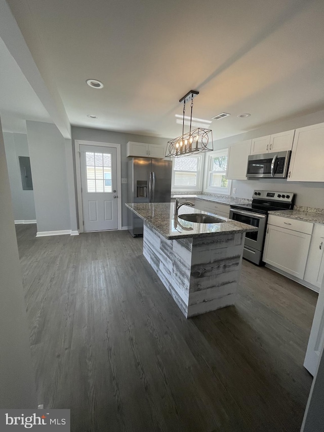 kitchen with dark wood-style flooring, stainless steel appliances, a healthy amount of sunlight, a sink, and light stone countertops