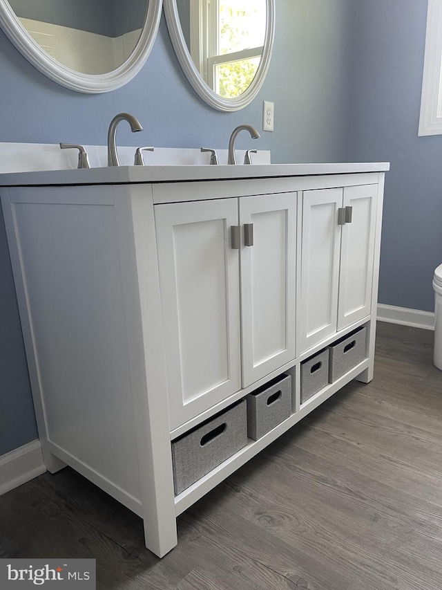 bathroom with a sink, baseboards, toilet, and wood finished floors