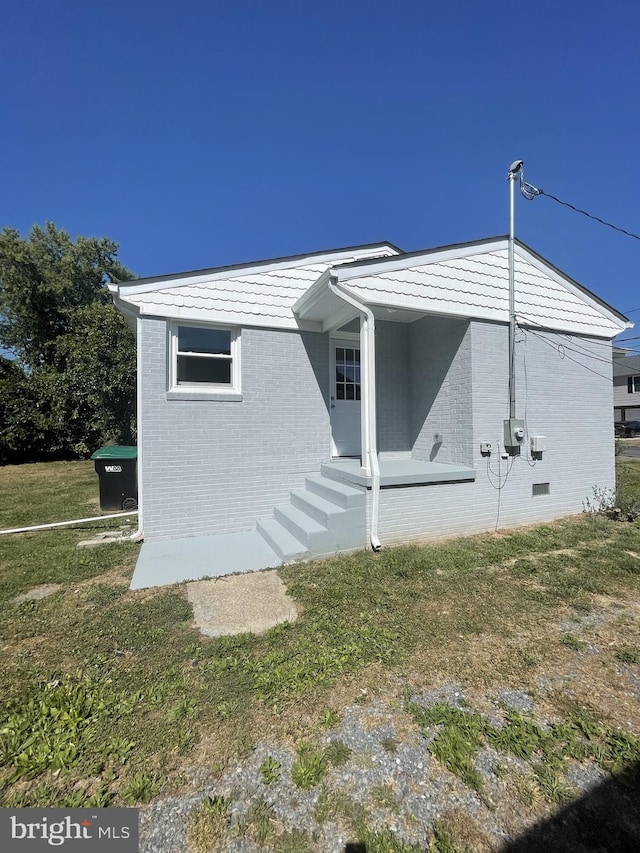 exterior space with crawl space, brick siding, and a front lawn