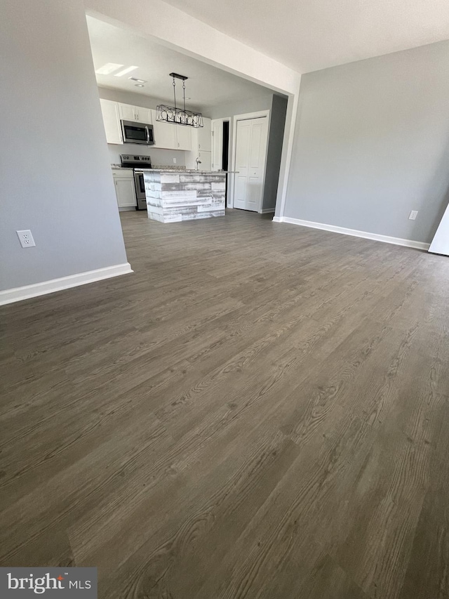 unfurnished living room with baseboards and dark wood finished floors