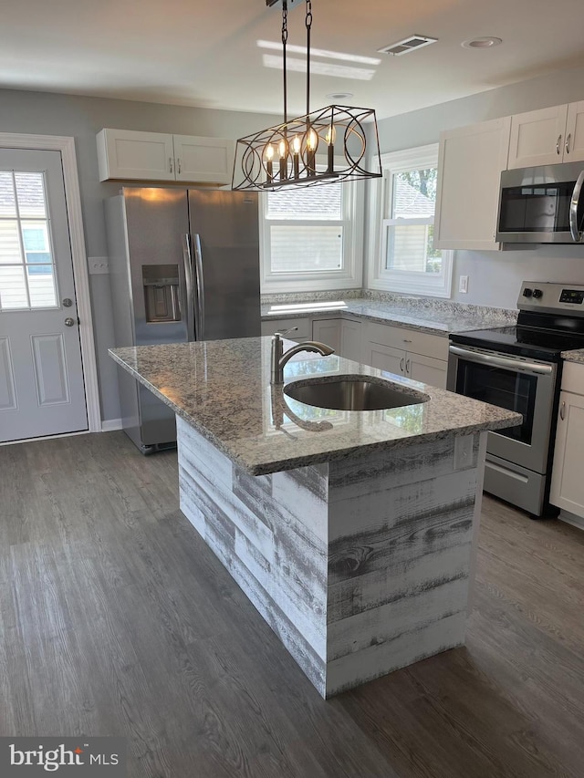 kitchen with light stone counters, a sink, visible vents, white cabinets, and appliances with stainless steel finishes