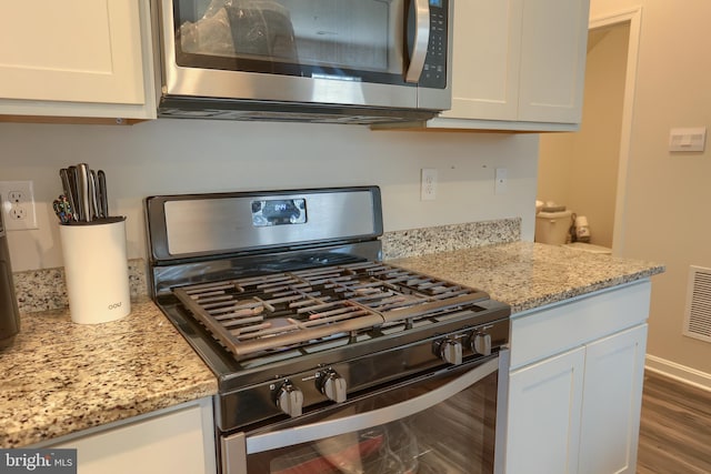 kitchen featuring white cabinetry, stainless steel appliances, and light stone counters