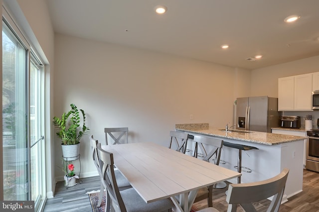 dining space with baseboards, wood finished floors, visible vents, and recessed lighting