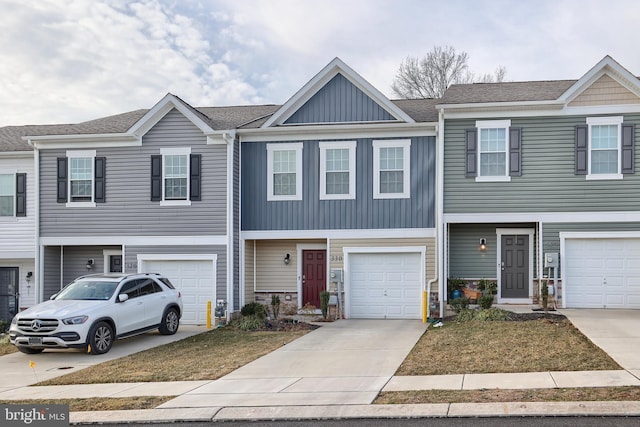 townhome / multi-family property with a garage, driveway, board and batten siding, and a shingled roof