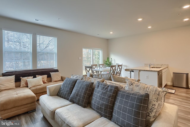 living room with light wood finished floors, visible vents, and recessed lighting