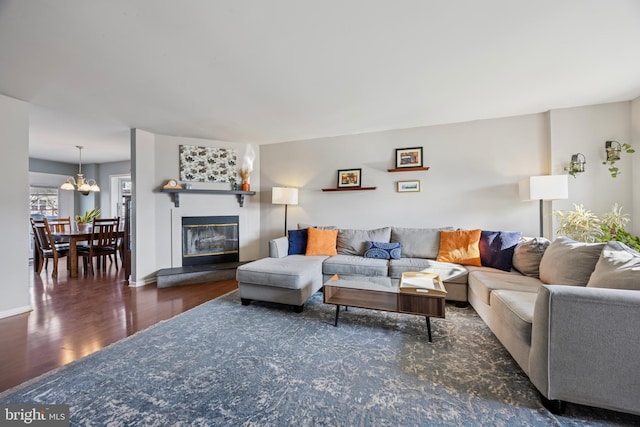 living area with baseboards, a chandelier, wood finished floors, and a glass covered fireplace