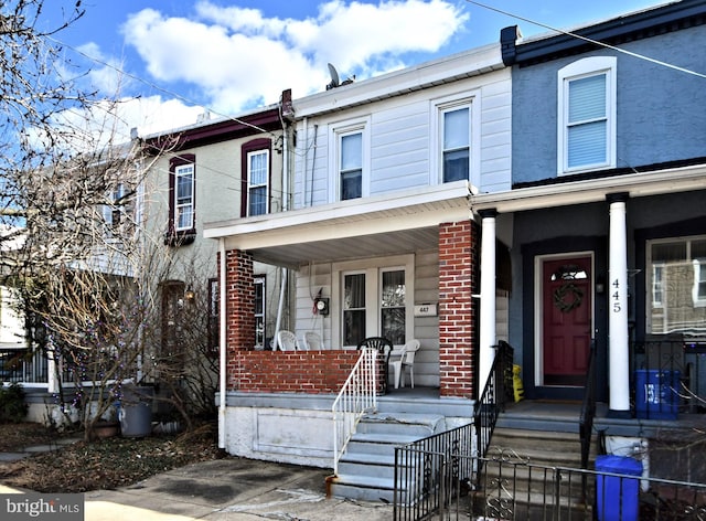 view of property with covered porch and brick siding