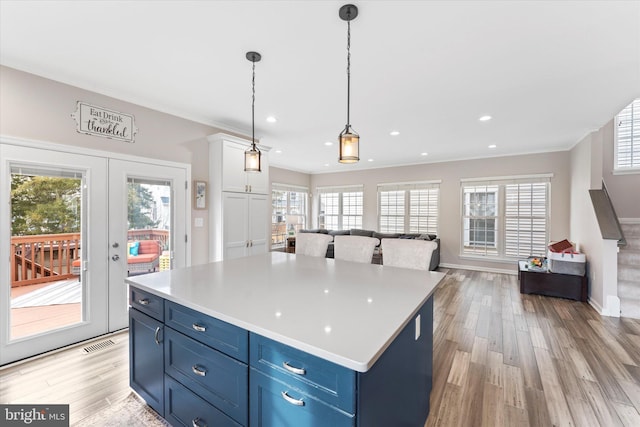 kitchen with visible vents, blue cabinetry, light wood-style flooring, and open floor plan