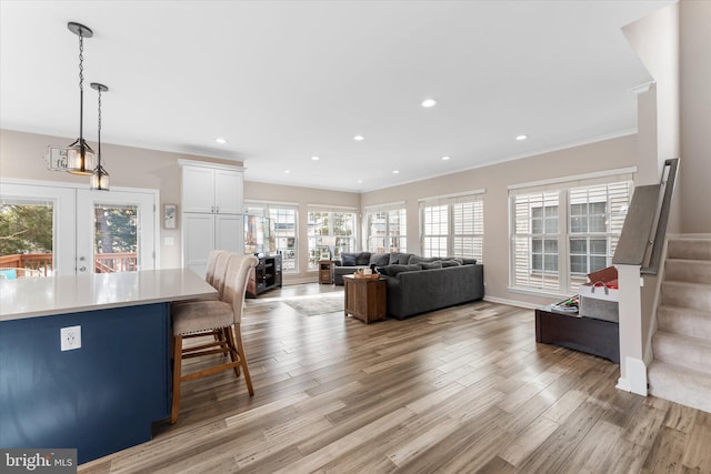 living area with stairway, light wood-style flooring, and crown molding