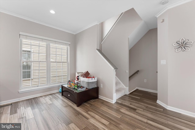 interior space featuring visible vents, baseboards, wood finished floors, and crown molding