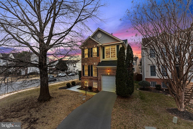 view of front facade featuring driveway, brick siding, and an attached garage