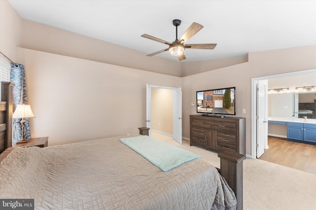 bedroom with ceiling fan, baseboards, ensuite bathroom, and light carpet