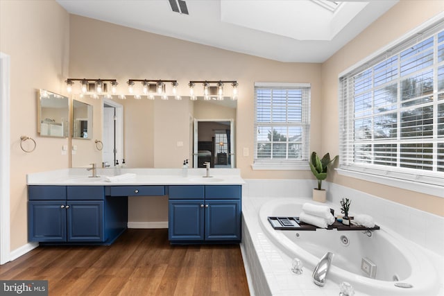 bathroom featuring wood finished floors, visible vents, a sink, lofted ceiling with skylight, and a jetted tub