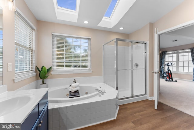 bathroom with vanity, wood finished floors, a skylight, a stall shower, and a whirlpool tub