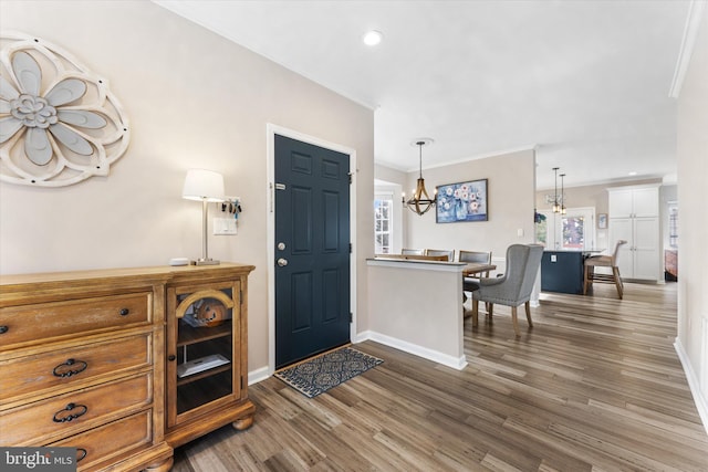 entryway featuring ornamental molding, wood finished floors, recessed lighting, baseboards, and a chandelier