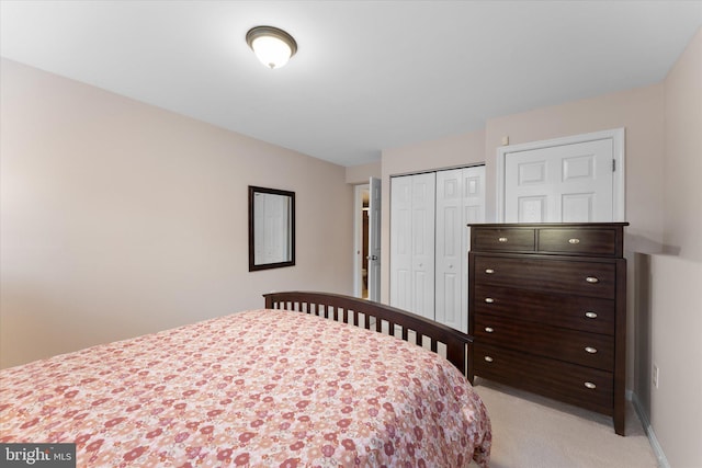 bedroom with baseboards, a closet, and light carpet