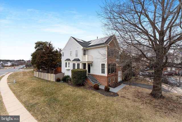 view of property exterior with roof mounted solar panels, a lawn, brick siding, and fence