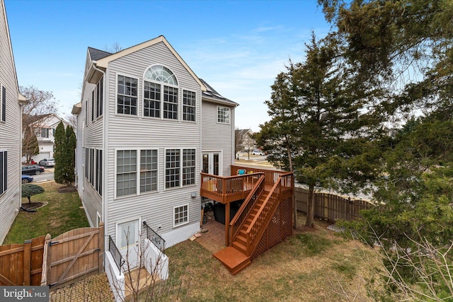 rear view of property with stairway, a gate, a wooden deck, a yard, and fence private yard