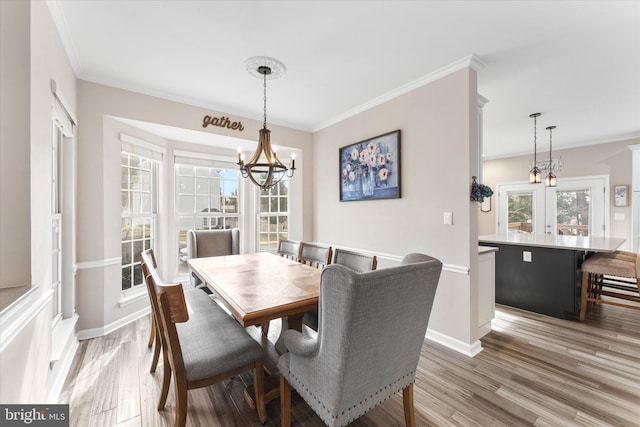 dining room with ornamental molding, baseboards, light wood finished floors, and a chandelier