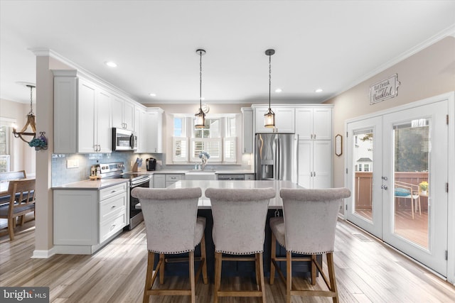 kitchen with a kitchen bar, a kitchen island, stainless steel appliances, light wood-style floors, and decorative backsplash