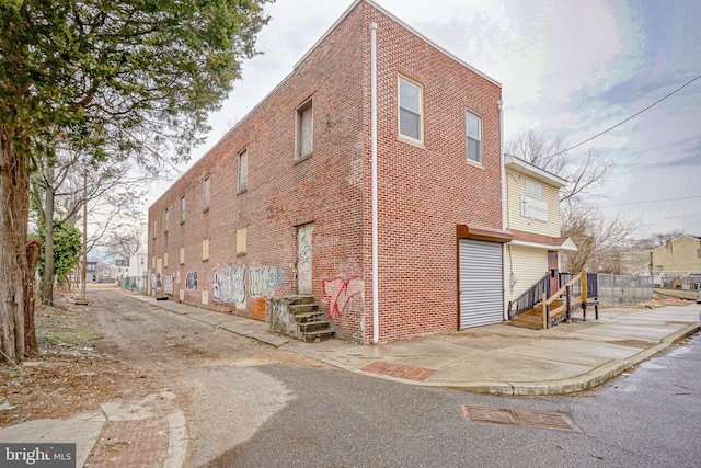 view of side of property with brick siding and fence